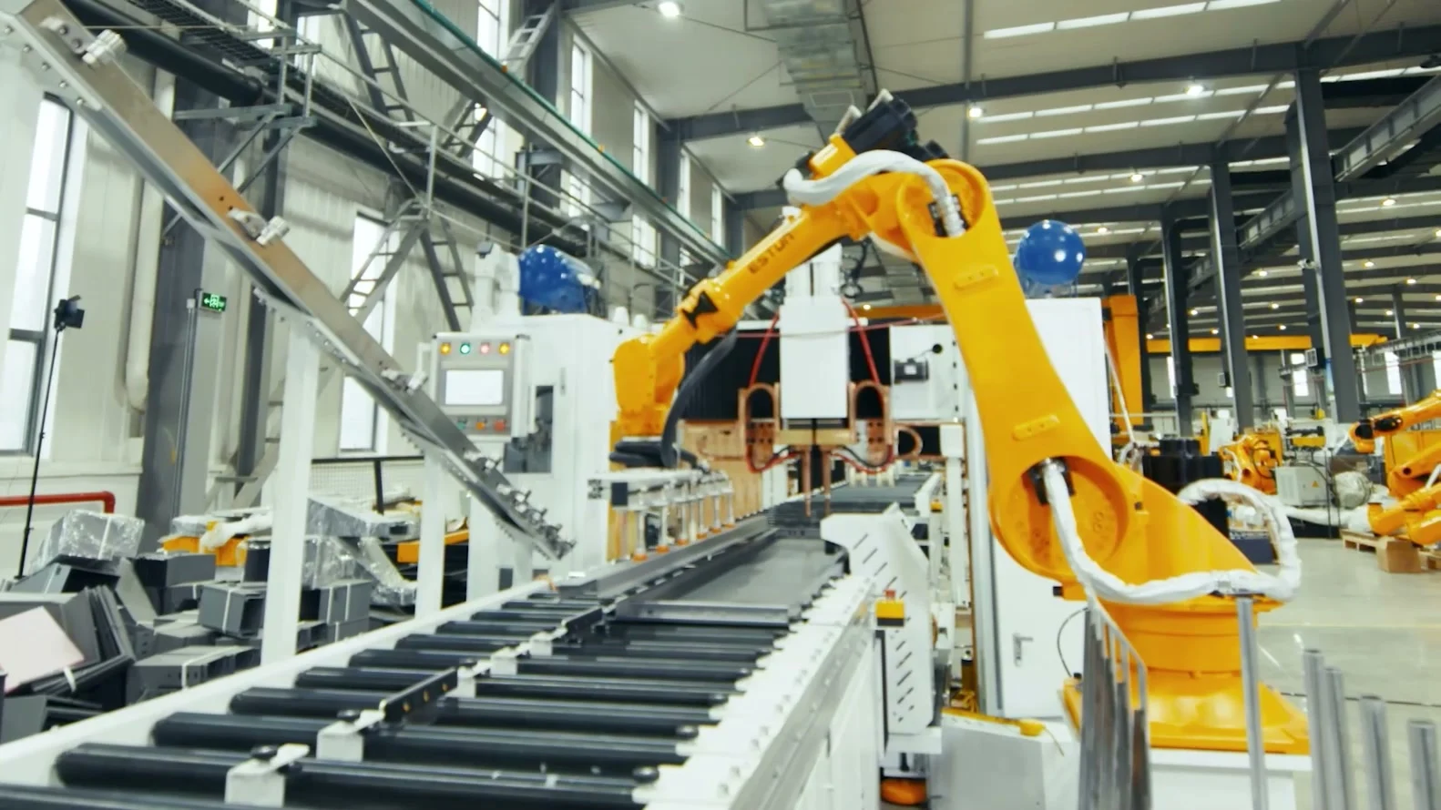 ESTUN robot arm with a gripper above a conveyor in a workshop.