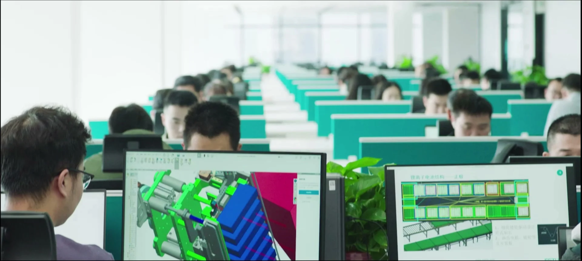 People working at three-dimensional design screens in a technical workspace.